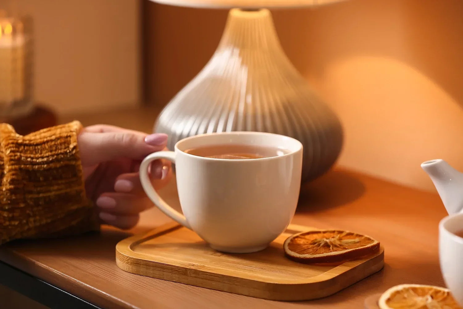 Hand holding a cup of tea in a café, showing why tea in Malaysia remain popular among customers who prefer tea bags.