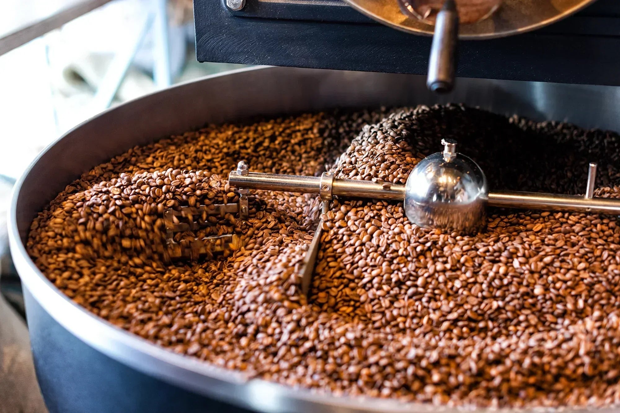 Freshly roasted coffee beans being cooled in a large roasting cylinder, highlighting the craftsmanship and quality control of coffee suppliers in Malaysia