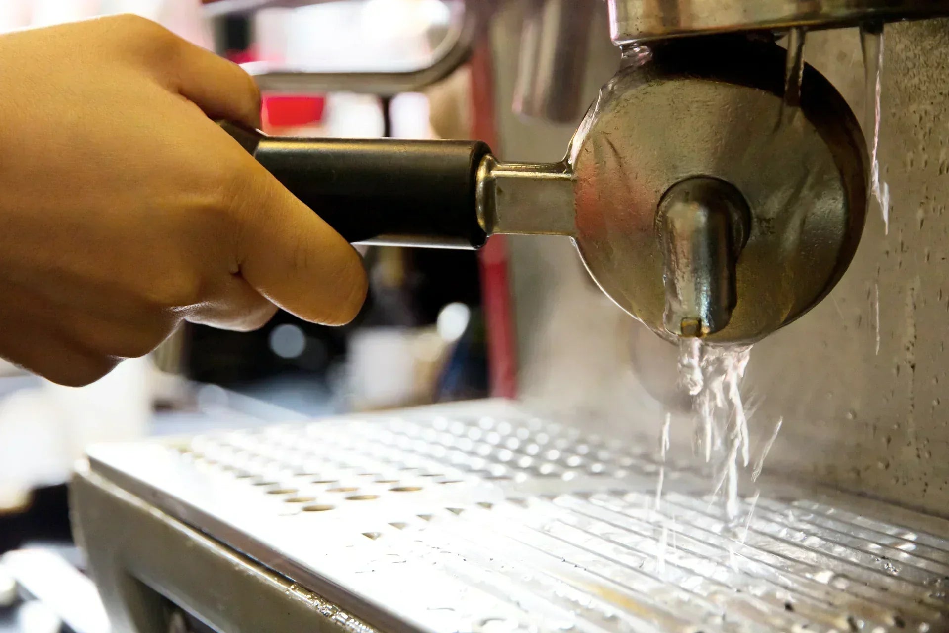 A home coffee brewer washing a coffee machine portafilter as part of a regular machine maintenance and descaling routine